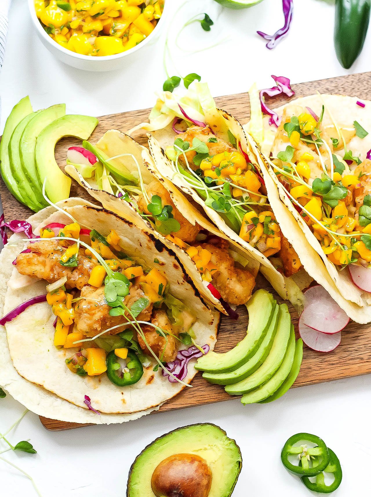 These grain free tacos is a fun and quick breaded fish recipe with easy mango salsa! Paleo fish tacos are totally gluten-free, family friendly, and even Whole30 if you skip the grain free tortilla and go for a lettuce wrap fish taco! Either way, these paleo fish tacos will be a summer favorite! #paleofishtacos #grainfreetacos #paleofish