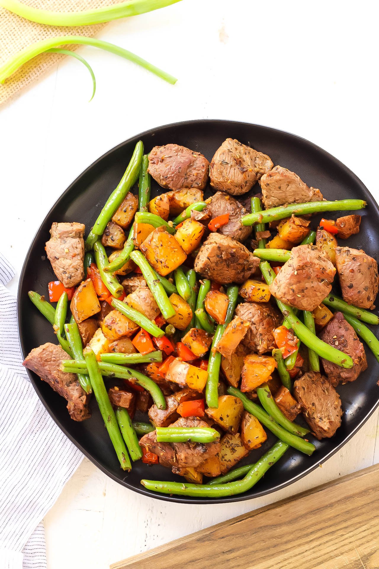 This easy Whole30 steak skillet is full of flavor and healthy veggies. It's a new favorite Paleo one pan meal around here that only takes 20 minutes! Making everything in one skillet is my go-to for quick meal prepping or making a clean eating and family friendly weeknight dinner. #whole30beefrecipes #whole30onepan #paleoonepan #paleobeefrecipes