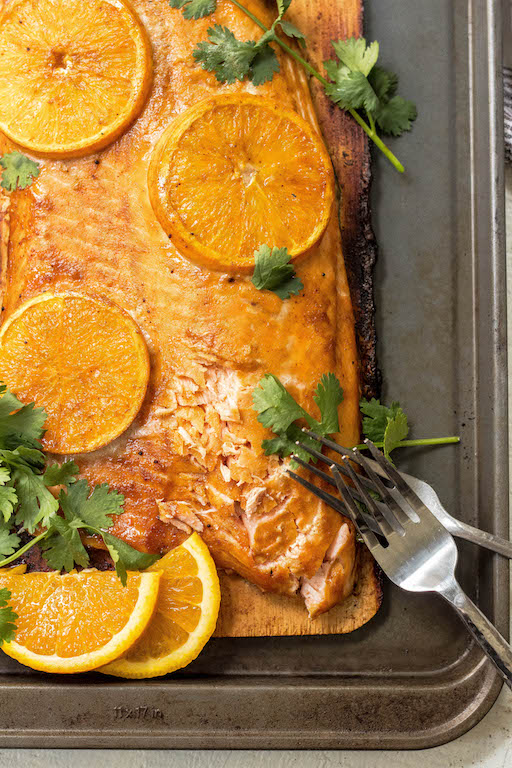 This Whole30 and Paleo orange glazed cedar plank salmon is every bit as delicious and easy as it looks! It's one of my favorite simple ways to cook salmon. The Paleo orange glaze takes a minute to put together and the cedar ramps up the taste of the salmon even more! #whole30salmon #whole30grilling #cedarplanksalmon