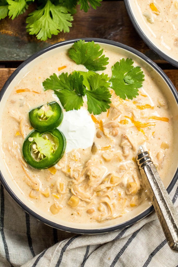 This slow cooker white chicken chili is a family recipe I grew up with, and it's every bit as hearty and delicious as it is easy to make. It's made with a few simple ingredients like white corn, shredded chicken, cream cheese, northern beans and the perfect spice combination. With only a couple of minutes of prep work, this hands off dinner is a great recipe for a chilly fall or winter night. #slowcookerchili #whitechickenchili #slowcookerwhitechickenchili