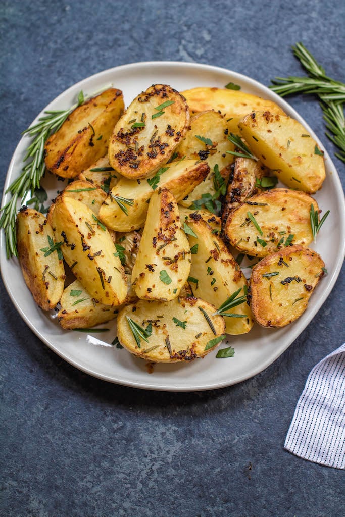These garlicky, herb and mustard roasted potatoes are baked to crispy perfection. This Whole30 and paleo side dish takes just minutes to throw together for an easy weeknight dinner and are delicious enough to be a crowd pleaser at any holiday meal. The potato side dish requires only a handful of simple ingredients, 30 minutes in the oven and reheats great for leftovers or breakfast #whole30sidedish #whole30potatoes #paleosidedish #mustardpotatoes