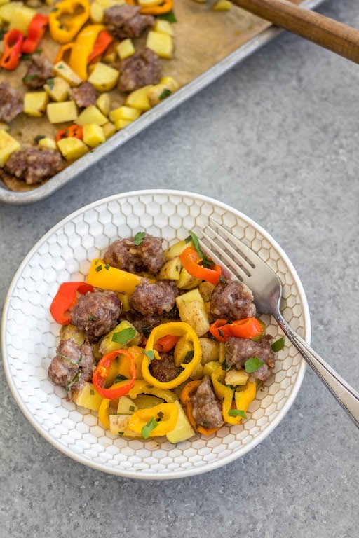 This easy sheet pan sausage breakfast recipe is a healthy meal prep recipe that's only 5 ingredients! The breakfast sausage is paired with seasoned potatoes and peppers all on one pan, put into the oven and ready to go with very little hands-on time. It's also great for a weeknight dinner for a simple vegetable and protein meal. This is a quick Whole30, paleo, gluten-free and egg-free breakfast recipe the whole family will enjoy! #whole30breakfast #whole30sheetpan #sheetpanbreakfast #glutenfree #eggfree #paleobreakfast