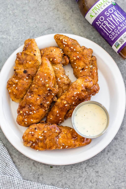 These oven baked teriyaki chicken tenders are easy to make, full of flavor and a family friendly dinner recipe everyone will enjoy. They're breaded in a paleo, Whole30 and gluten-free coating, baked and tossed in a sticky, delicious soy-free teriyaki sauce. These tenders are great on their own dipped into your favorite sauce, or over a big salad, and perfect for a quick weeknight meal. #whole30chicken #whole30teriyakichicken #teriyakichickentenders #paleochicken #glutenfreechicken #whole30chickentenders