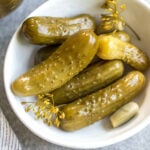 This recipe for canned pickles has been in my family for over 100 years. It's easy, even for a canning beginner, only requires 7 ingredients, including garlic, dill and onions to give them their classic flavor. The mini cucumbers can be crinkle cut into slices, cut into spears, or left whole. This homemade dill pickle recipe yields 40 jars, so you can enjoy them all year, share with family and give as gifts! #homemadepickles #dillpickles #picklerecipe #picklebrine