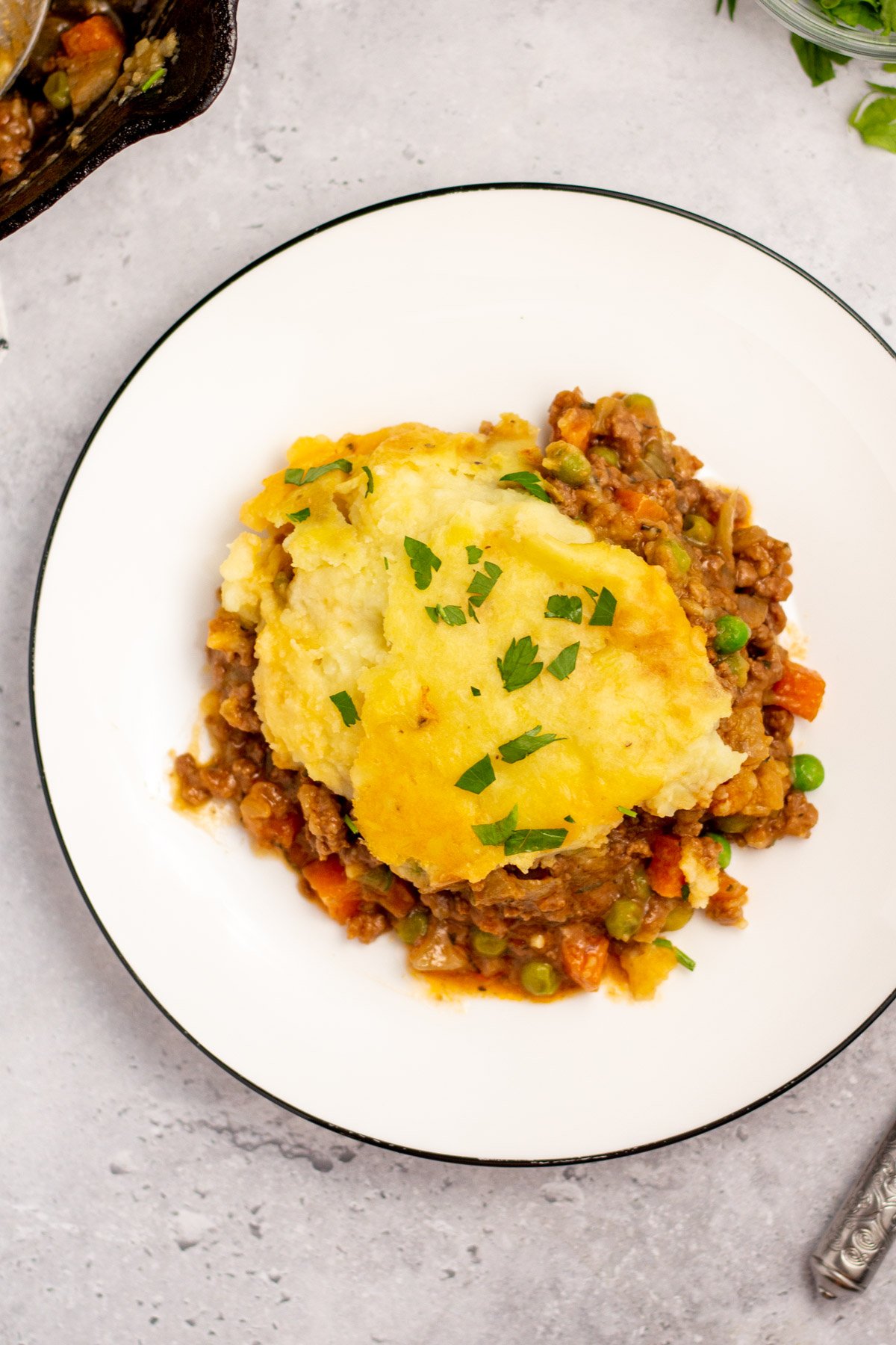 This Whole30 Shepherd's Pie recipe is baked in an oven proof skillet which makes the cooking process simple and easy. It's also a budget-friendly ground beef recipe that's paleo, gluten-free, dairy-free and can be made low carb. With vegetables like carrots, onions, celery and peas mixed in with a flavorful gravy, the filling is a perfect companion for the creamy mashed potatoes. It's a hearty, cozy recipe that's family friendly and also great for meal prep! #groundbeefrecipes #whole30beef #whole30recipes #paleogroundbeef