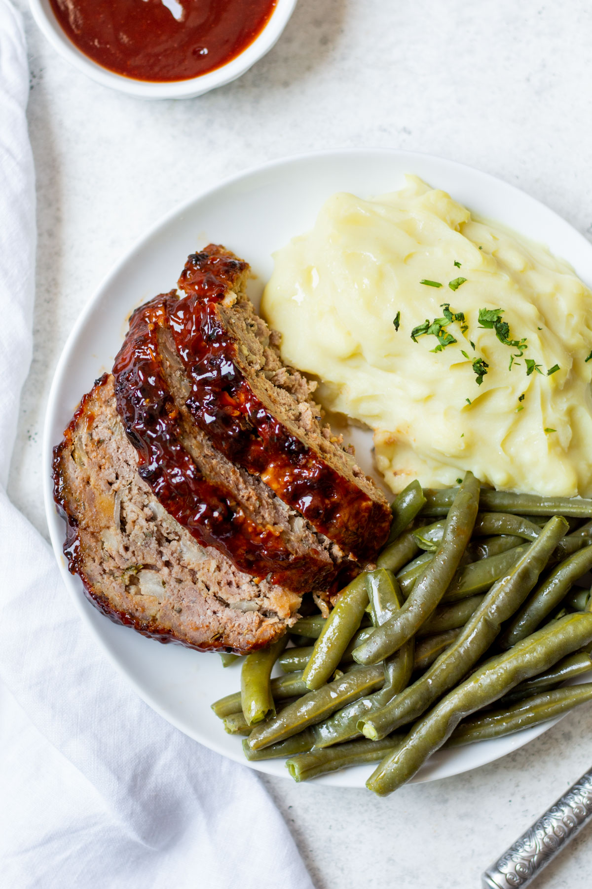 This air fryer meatloaf is a great, healthy recipe for getting a classic meal on the table for dinner. It uses very few ingredients and can be made gluten free easily. The air fryer caramelizes the sauce to perfection and makes for a juicy, flavorful meal. Use this meatloaf for an easy meal prep for the week ahead or divide the recipe into two loaves to save some to freeze for later. #glutenfreerecipes #healthydinnerrecipes #beefrecipes #airfryerrecipes #meatloaf