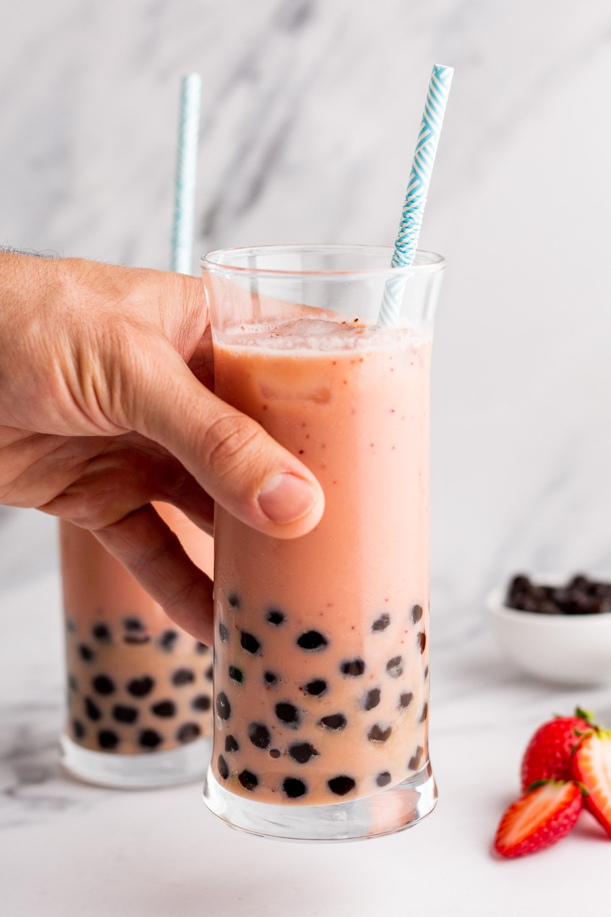 raising a glass of fresh strawberry boba tea